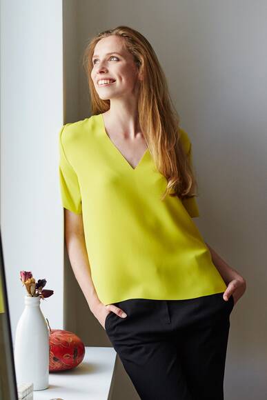 Smiling Woman Looking Through Window At Home